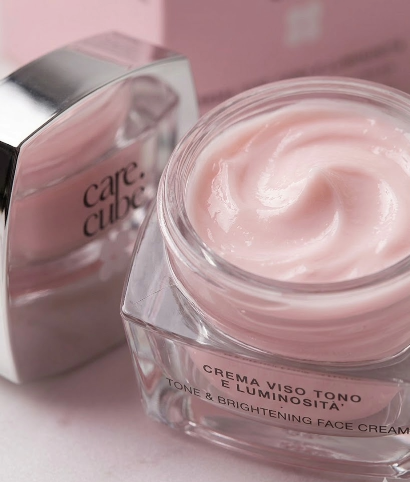 Crema viso tono e luminosità, prodotto cosmetico rosa in vasetto trasparente con coperchio argentato