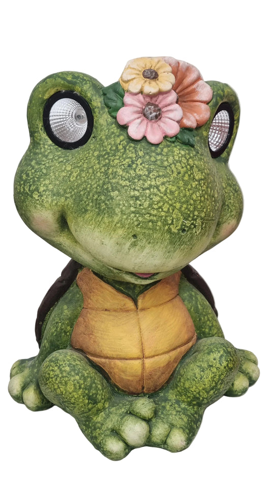 Statua decorativa rana verde con occhi riflettenti e fiori colorati sulla testa